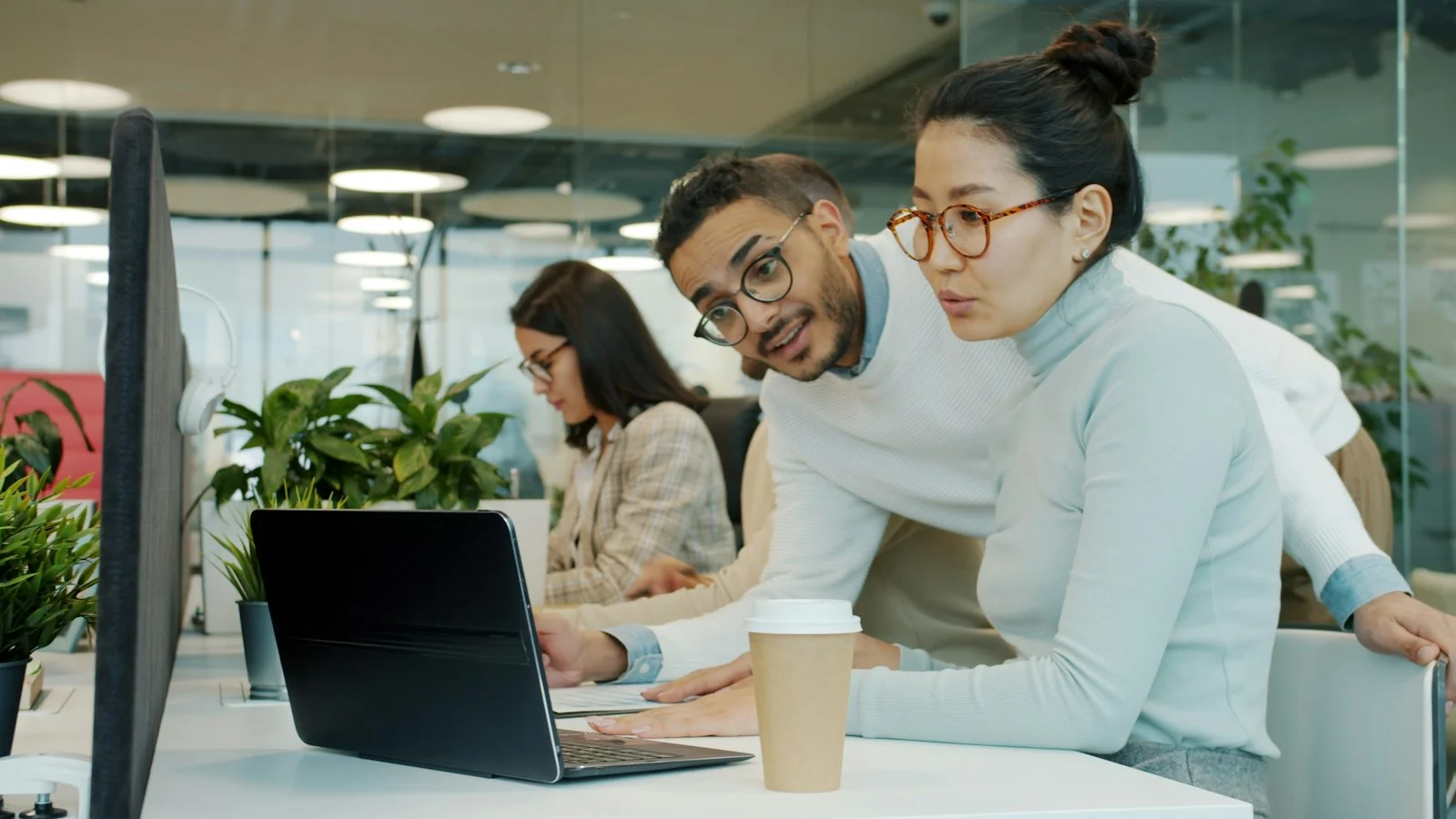 Two colleagues talking while looking at a laptop in an office