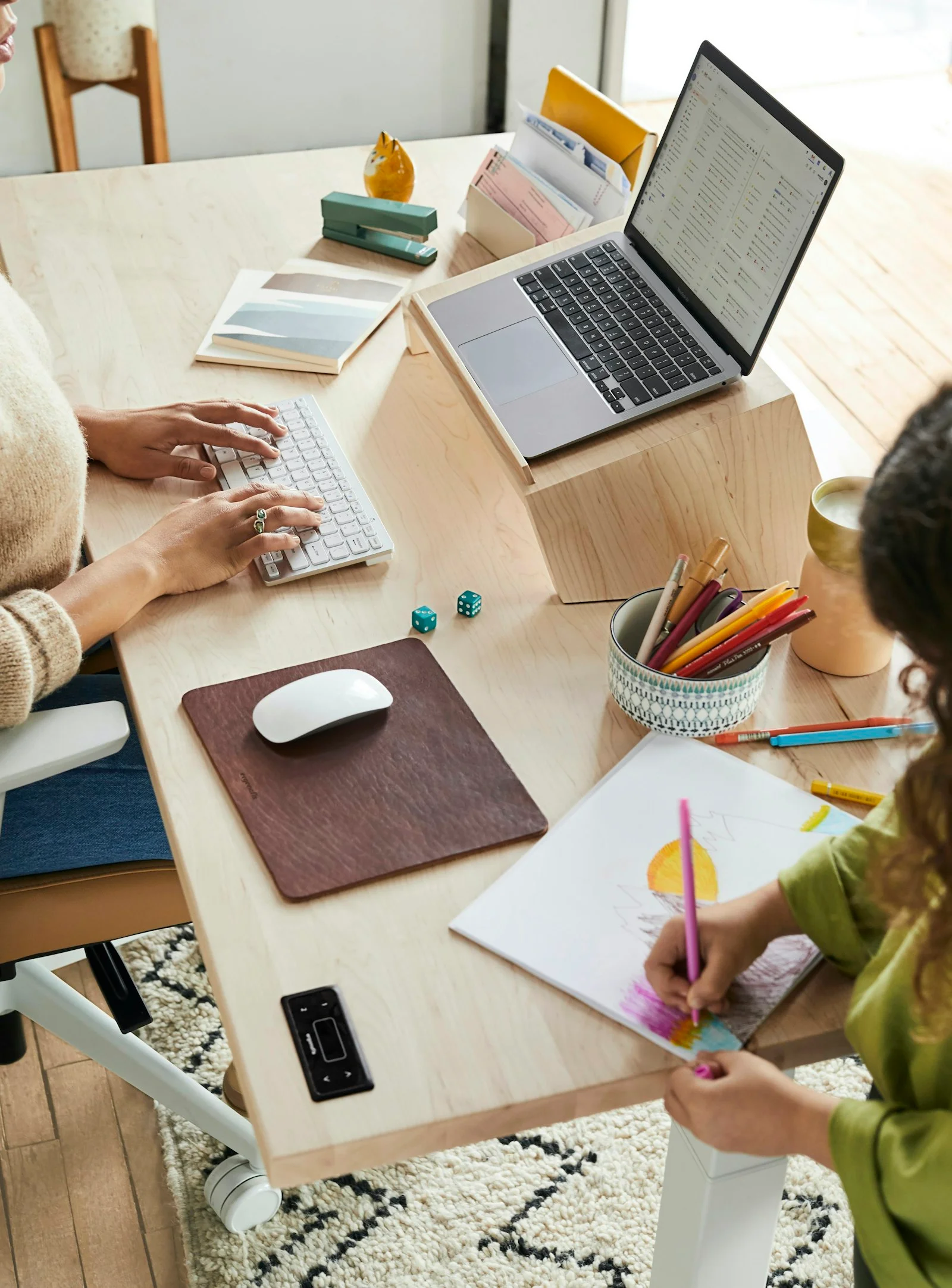 Woman sitting at a table with a child, using a laptop